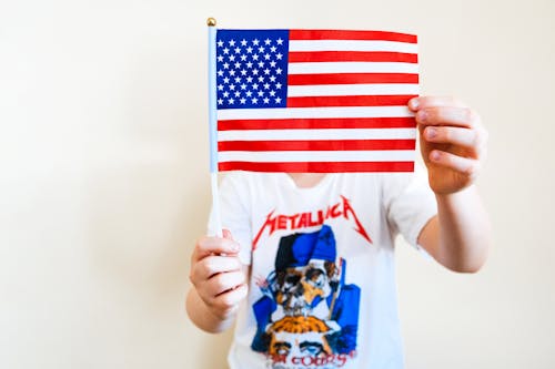 Man in Metallica Shirt Holding an American Flag Over His Face 