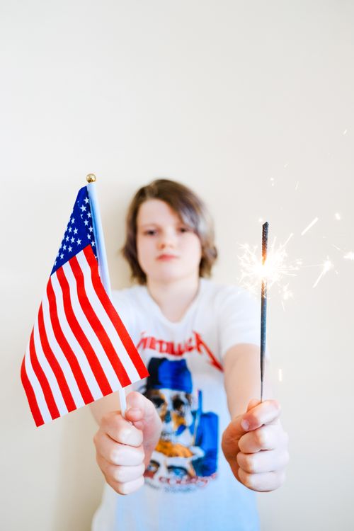 Free A young boy holding a sparkler and American flag, celebrating Independence Day. Stock Photo