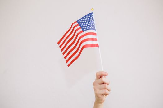 特写镜头：一只挥舞美国国旗的手，背景为中性色调
