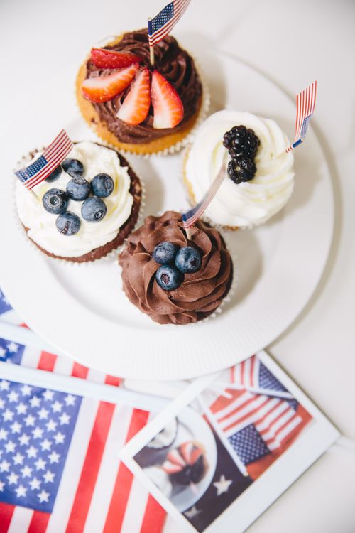Free Festive 4th of July cupcakes topped with fresh berries and mini American flags. Stock Photo