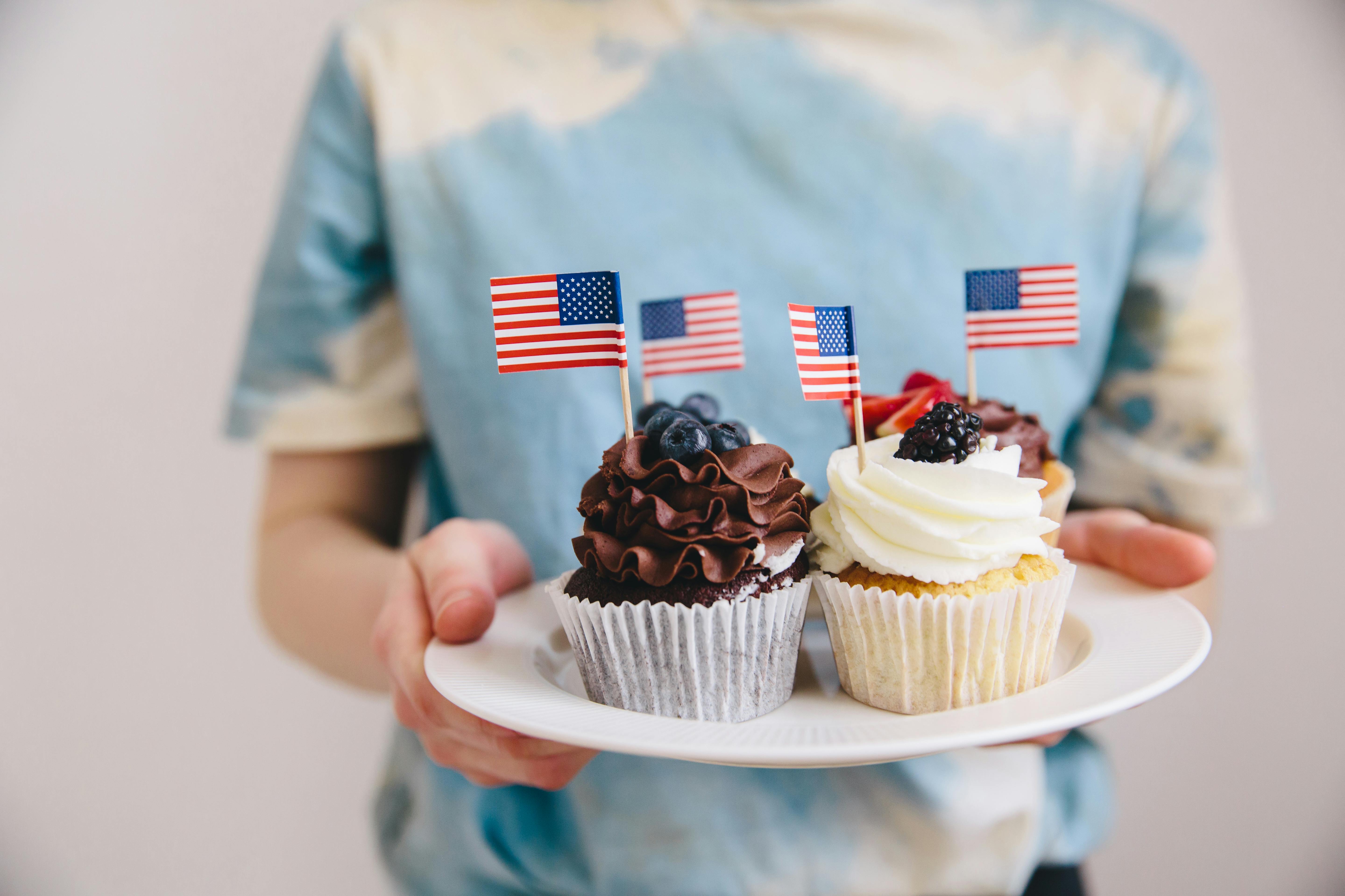 Close-up of cupcakes with American flags held on a plate, celebrating USA.