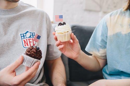 Close up of Hands Holding Cupcakes with Flags of USA