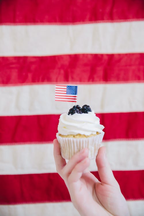 Small American Flag on a Cupcake held by a Person 