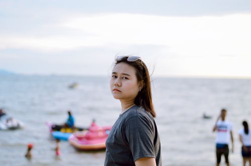 Free A young woman with sunglasses at a lively beach on a bright day. Stock Photo