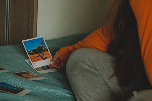 Faceless woman choosing pictures on bed