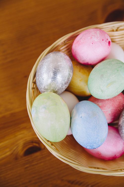 Free Vibrant pastel Easter eggs in a basket on a wooden table, perfect for holiday decoration. Stock Photo