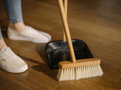 Free Person Wearing White Pants and White Socks Standing Beside Brown Broom Stock Photo