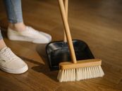 Person Wearing White Pants and White Socks Standing Beside Brown Broom
