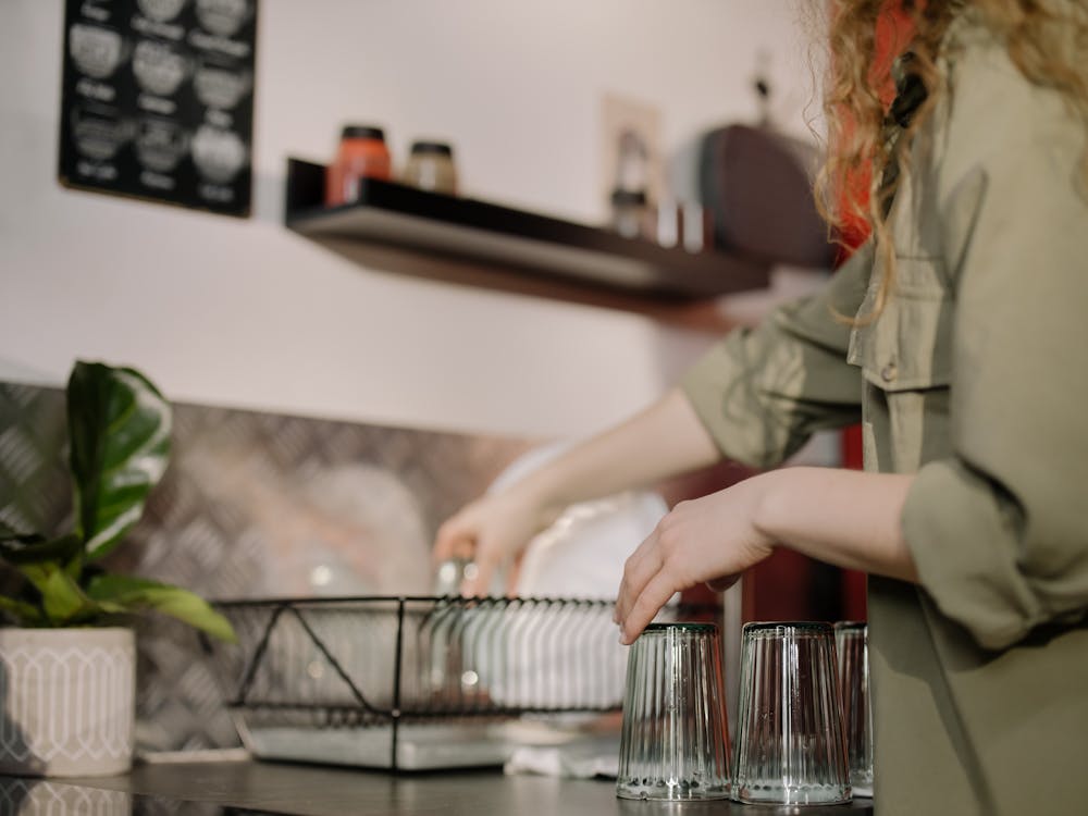 Free Woman in Gray Long Sleeve Shirt Holding Clear Glass Container Stock Photo