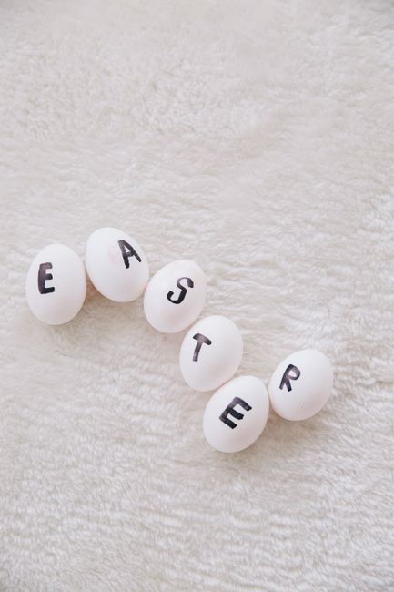 White eggs spelling 'Easter' arranged on a soft texture, perfect for seasonal designs.