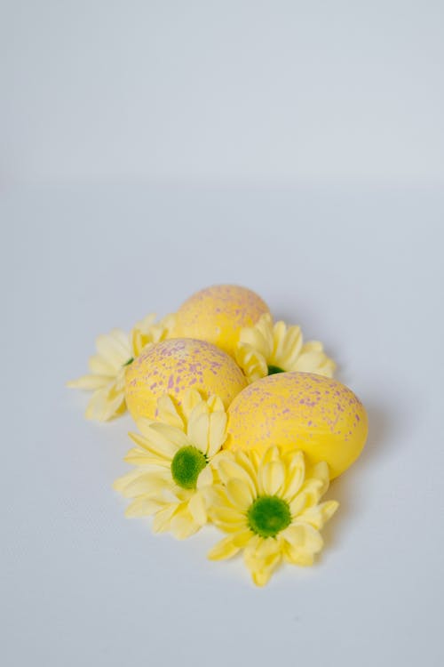 Yellow Flowers and Easter Eggs on White Surface