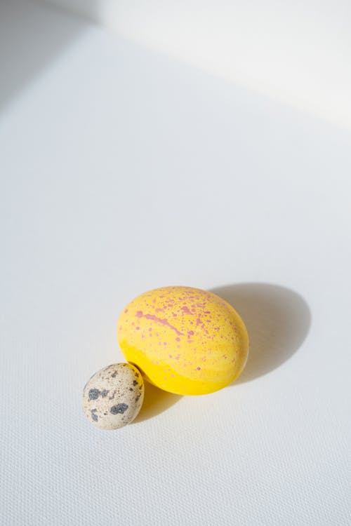 Yellow Easter Egg and Quail Egg on White Background