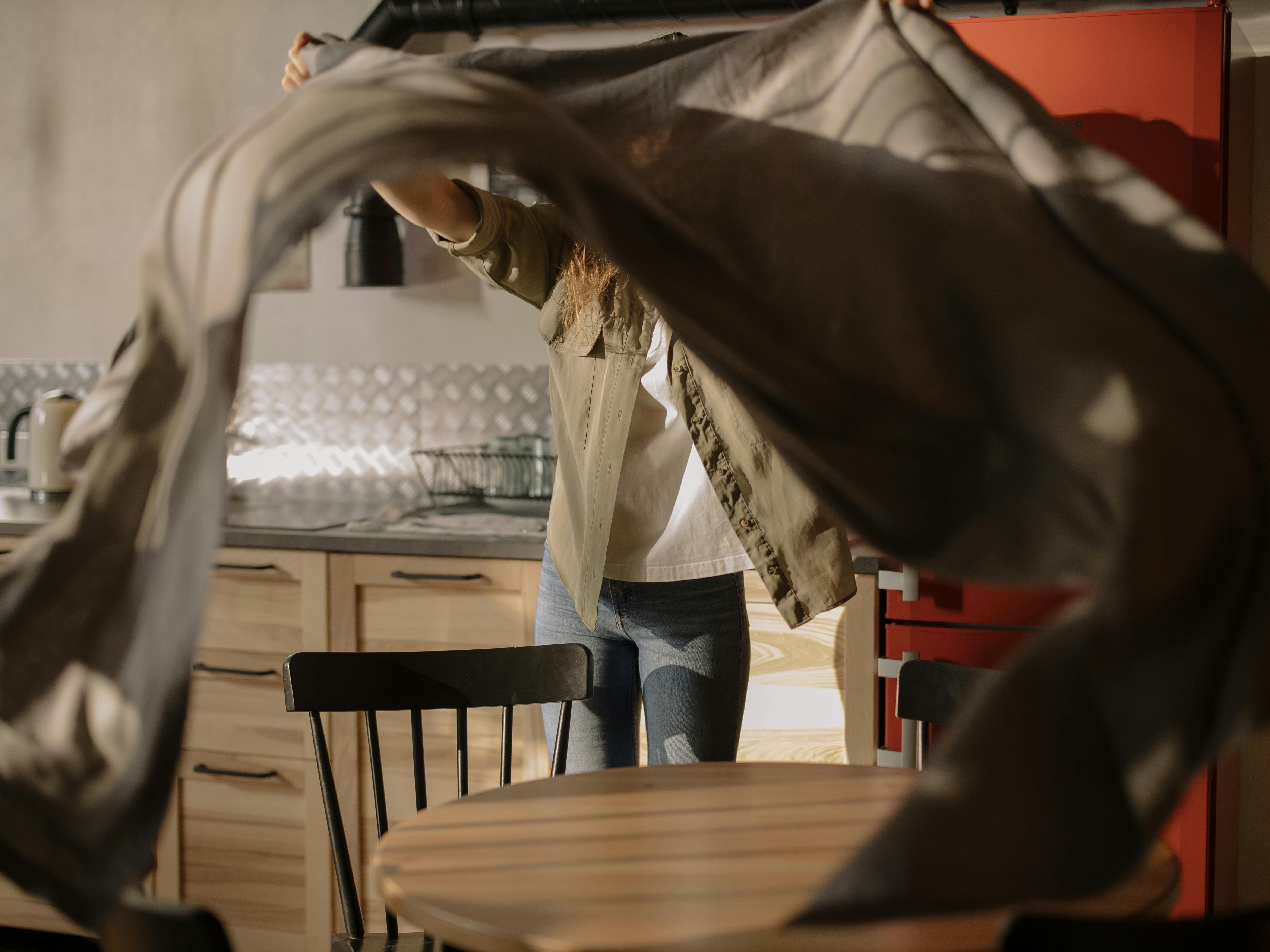 person in white long sleeve shirt and blue denim jeans standing beside brown wooden table