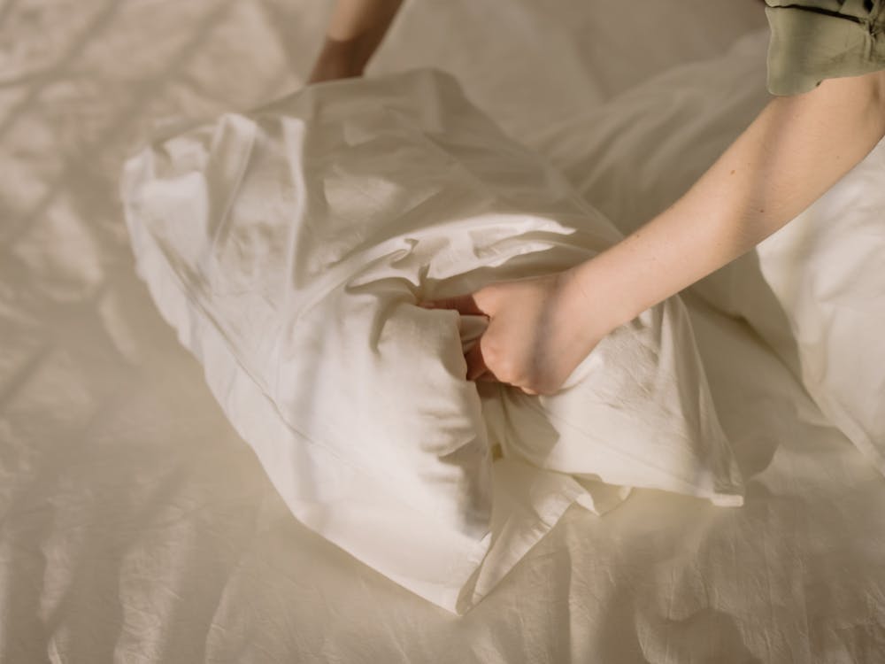Free Person Holding White Textile on White Bed Stock Photo