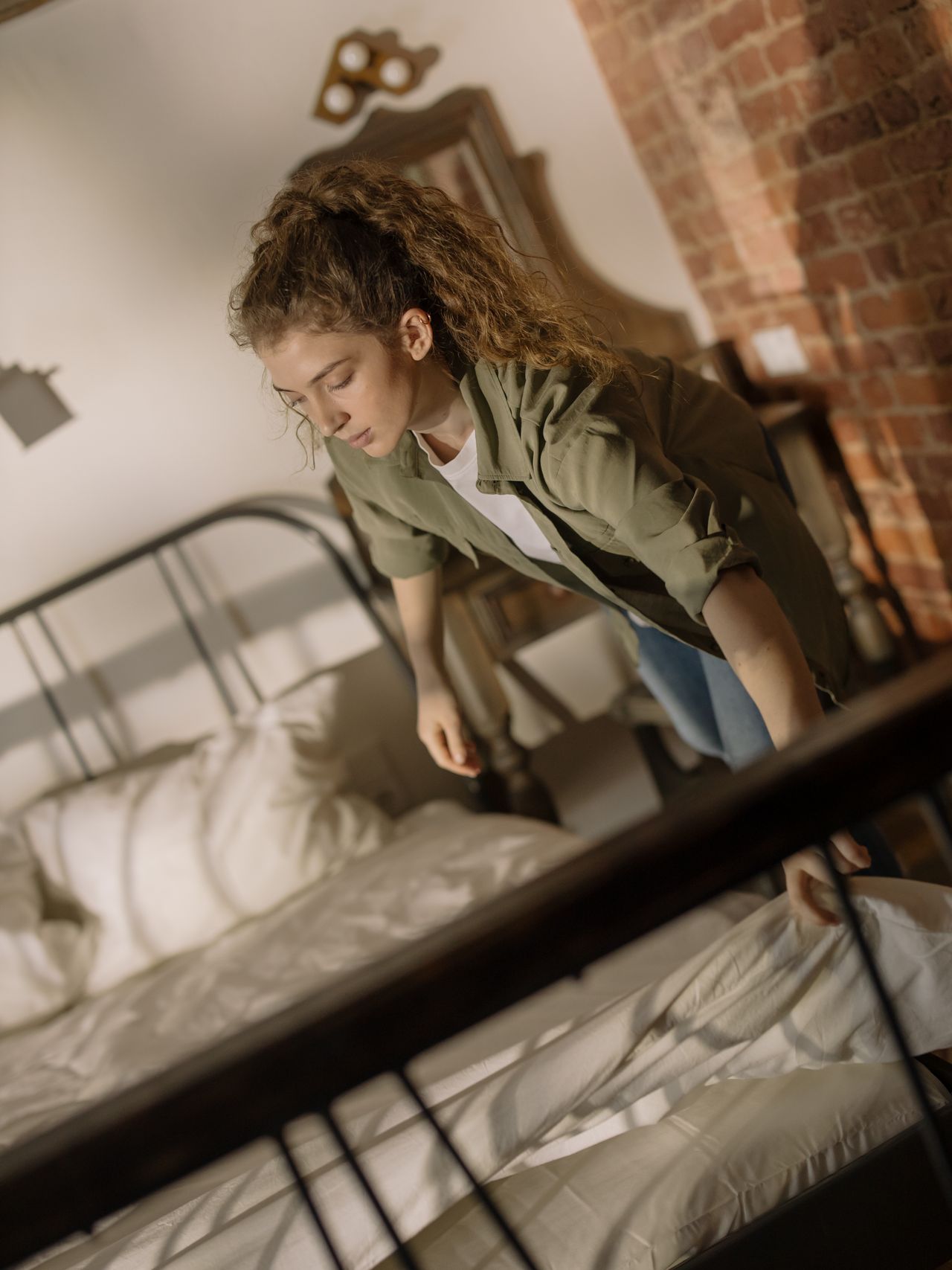 Woman smoothing fresh white sheets on a bed