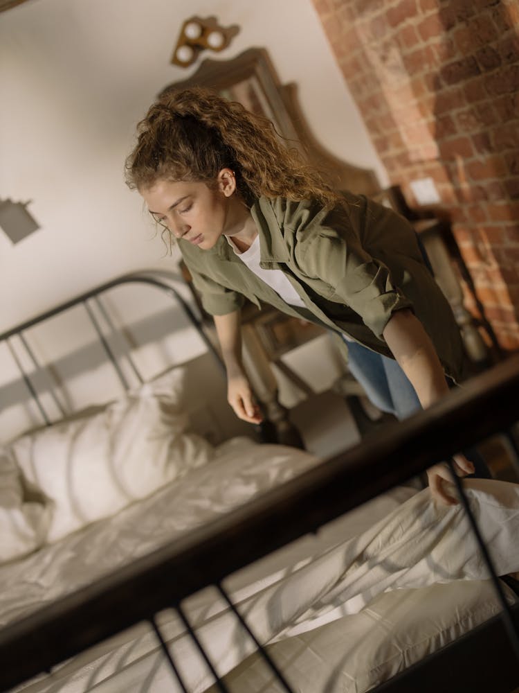 Woman In Green T-shirt And Black Pants Standing On Bed