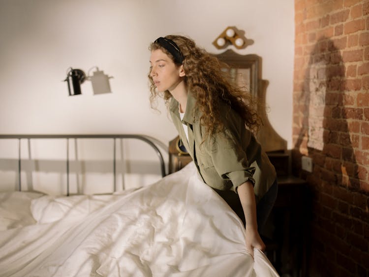 Woman In Gray Dress Sitting On Bed