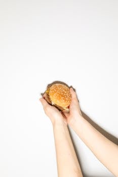 Delicious burger held by hands against a clean white background. Ideal for food photography.