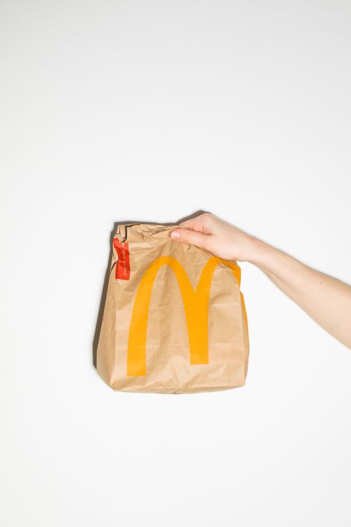Free Clean product shot of a hand holding McDonald's branded paper bag. Stock Photo
