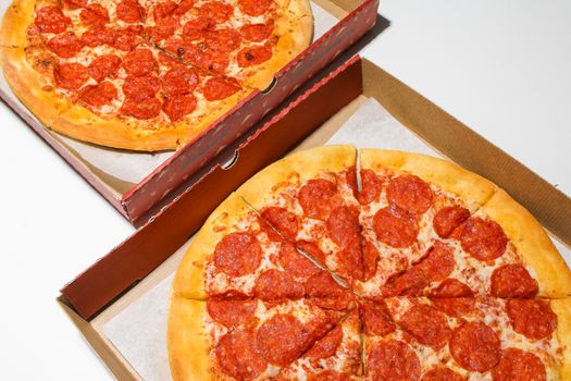 Photo by Polina Tankilevitch Top view of freshly baked pepperoni pizzas in open delivery boxes, ready to eat.