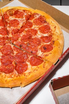 Freshly baked pepperoni pizza in an open cardboard box, cheese melted perfectly.