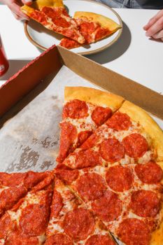 High-angle view of pepperoni pizza slices in a cardboard box, ready to eat.