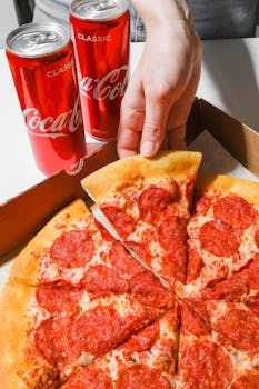 Close-up of pepperoni pizza with two cans of cola, perfect for a casual meal.