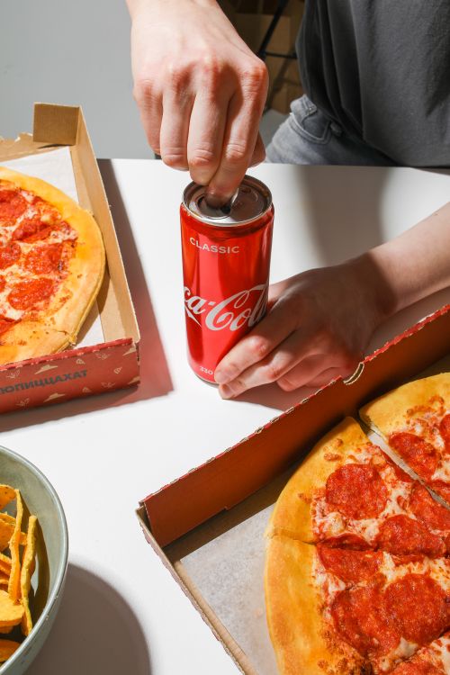 Free Person opening a soda can next to pepperoni pizza, ready to enjoy a delicious meal. Stock Photo