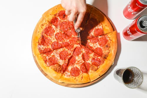 Free Person Slicing A Pizza With A Pizza Cutter Stock Photo