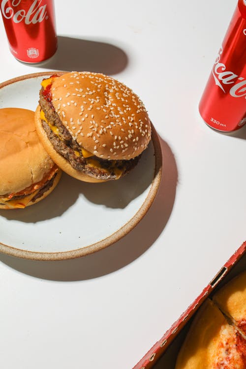 Free Burgers on Plate Beside Coca Cola Cans Stock Photo