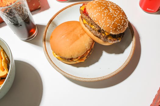 Juicy cheeseburgers with a refreshing soda and chips on the side, perfect fast food delight.