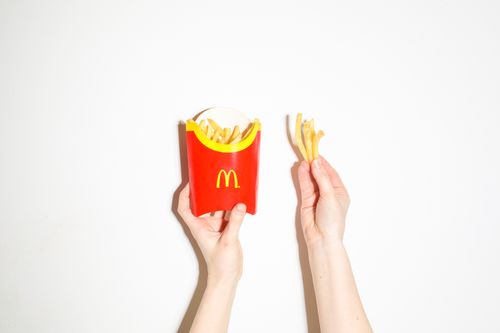 Free Close-up of hands holding McDonald's french fries against a white background. Stock Photo