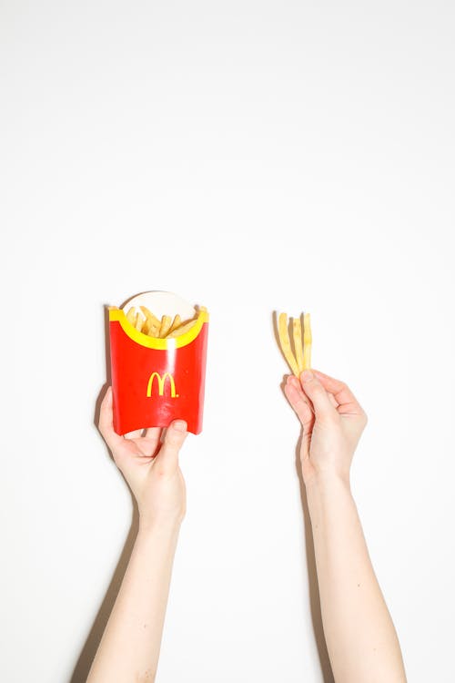 Person Holding Pieces of Fries 