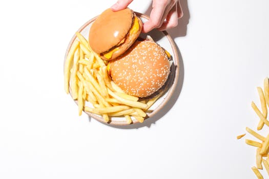 A top view of two cheeseburgers and fries on a plate, set against a white backdrop.
