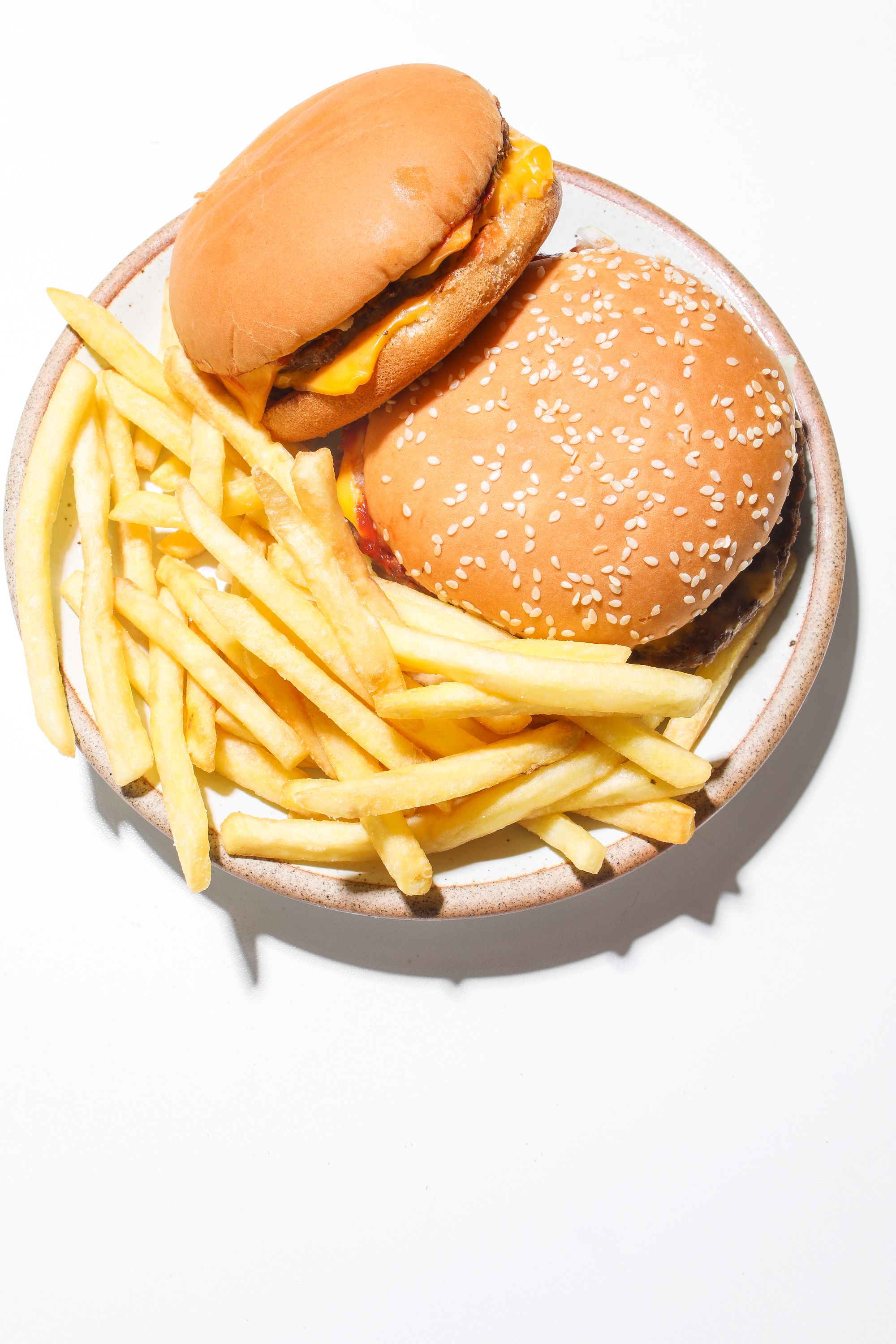 Two mouthwatering burgers and fries served on a plate, a perfect fast food meal.