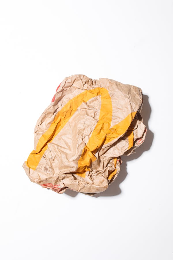 Top view of crumpled empty craft paper bag of fast food restaurant placed on white background illustrating recycle garbage concept