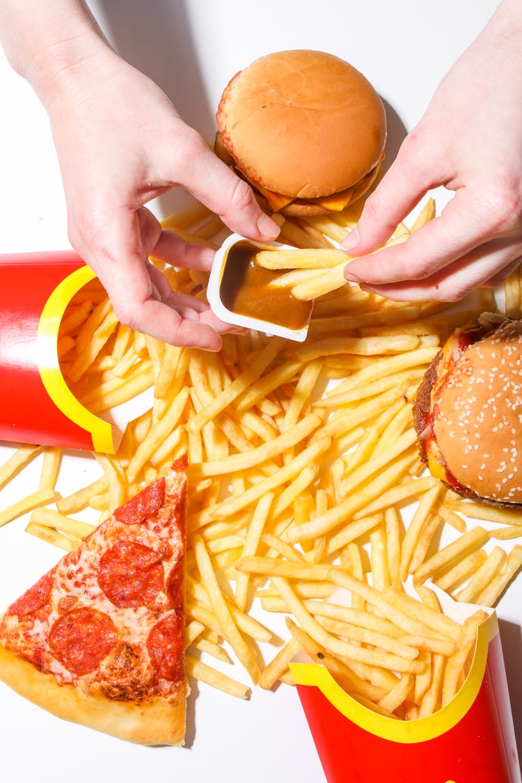 Person Dipping French Fries In A Sauce 