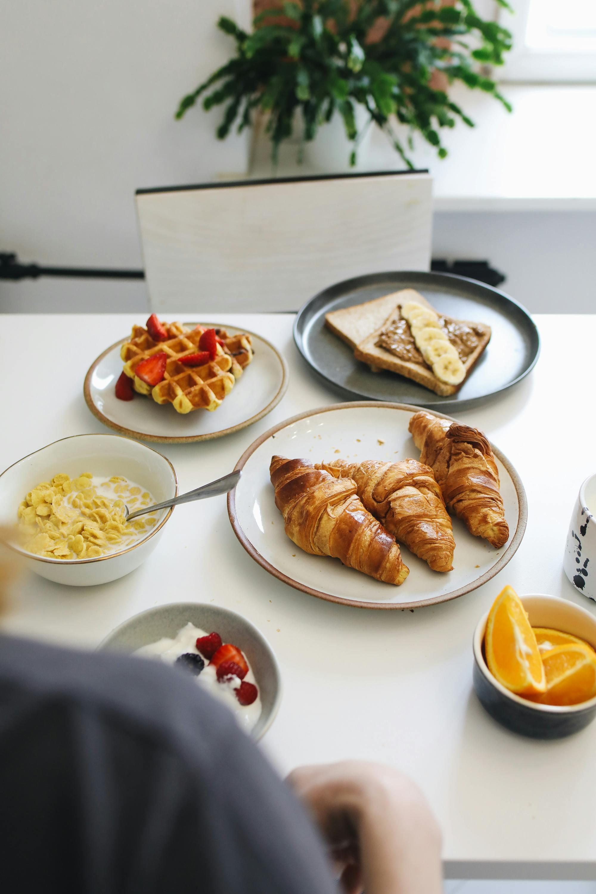 Inviting continental breakfast spread with croissants, waffles, and fresh fruit on a modern table.