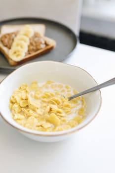 Close-up of a healthy breakfast featuring cornflakes in a bowl and banana toast.