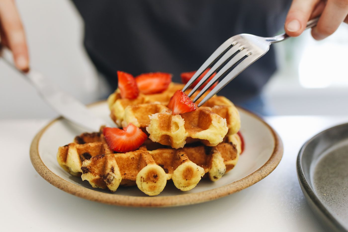 Golden waffles topped with strawberries on a white ceramic plate