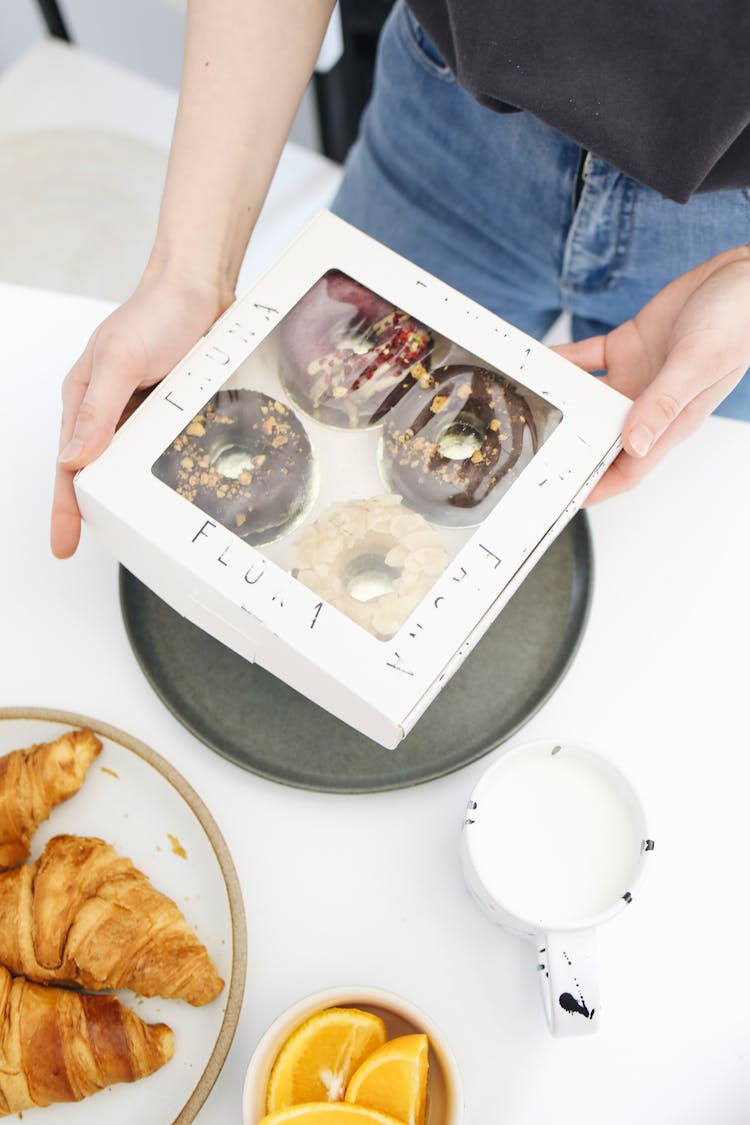 A Person Holding A Box Of Donut