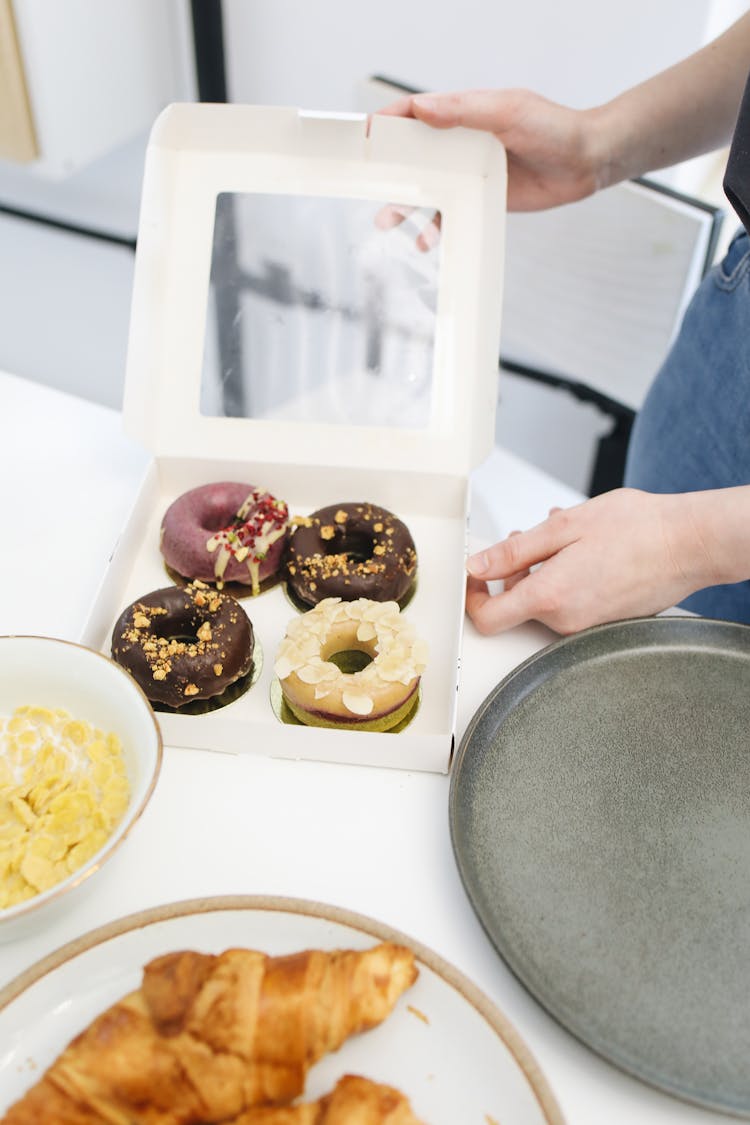 A Person Holding A Box Of Donuts