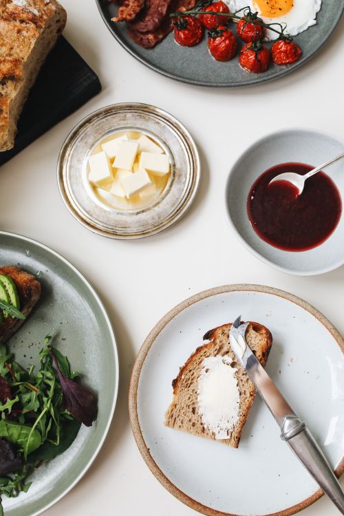 Free A top-down view of a breakfast spread featuring fresh bread, butter, eggs, and salad. Stock Photo
