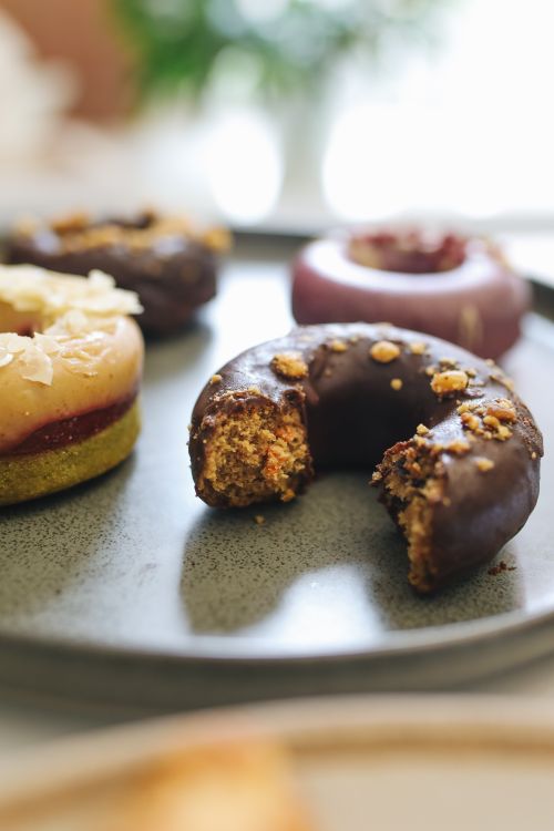 Free A delicious array of gourmet donuts with a focus on one with a bite taken out. Stock Photo