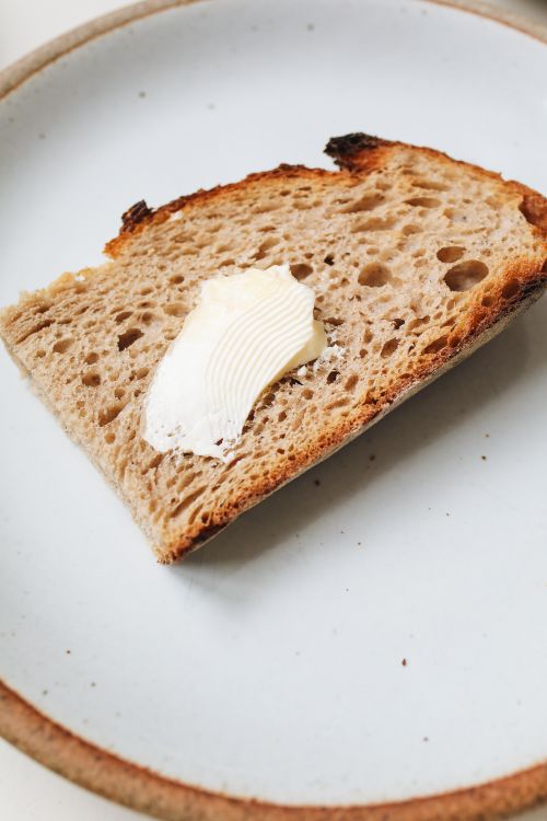 Free A detailed view of a buttered sourdough slice on a plate, perfect for breakfast. Stock Photo