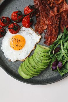美味的早餐包括酥脆的培根、煎蛋、鳄梨片、西红柿和蔬菜