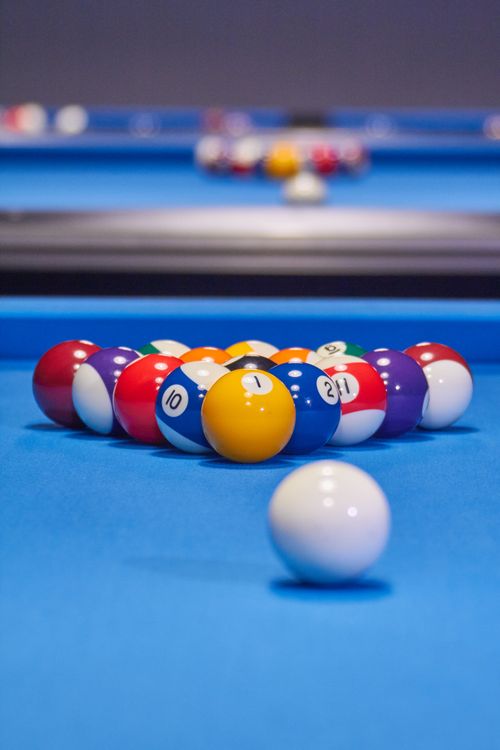 Free Close-up shot of billiard balls arranged in a triangle on a vibrant blue table, ready for a game. Stock Photo
