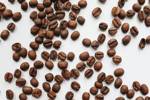 Free Roasted coffee beans artfully scattered on a clean white background, ideal for food and coffee-themed projects. Stock Photo