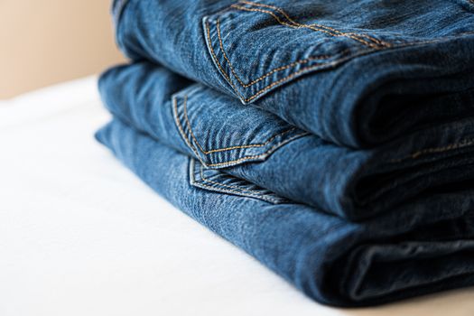 Stack of neatly folded blue denim jeans highlighting stitching details.