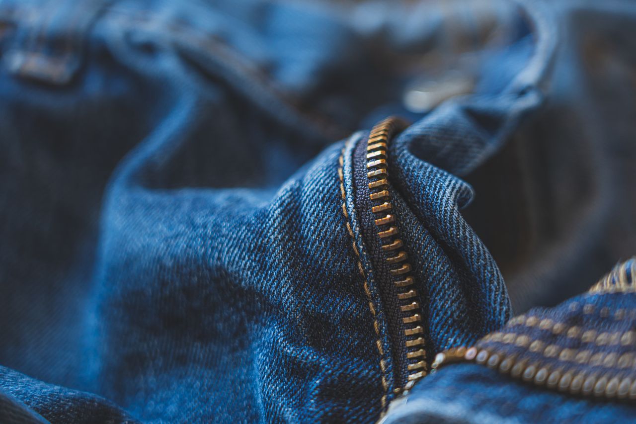 detailed close up of a blue denim jeans zipper with a soft focus